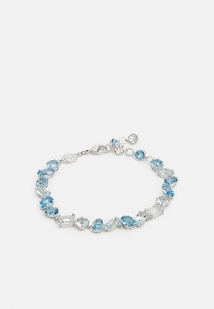 Pulsera de tono plateado que presenta piedras preciosas azules y transparentes de diversas formas, incluyendo ovaladas y rectangulares, unidas entre sí con un cierre de langosta.