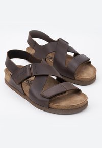 Brązowe skórzane sandały z krzyżującymi się paskami, zamszowa wkładka i conturowana korkowa podeszwa. Regulowany pasek na pięcie zapewniający pewne dopasowanie.
