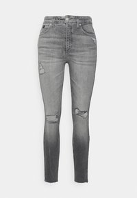 Jeans ajustados en denim gris desgastado, con parches desgastados en los muslos, dobladillo deshilachado y diseño clásico de cinco bolsillos.
