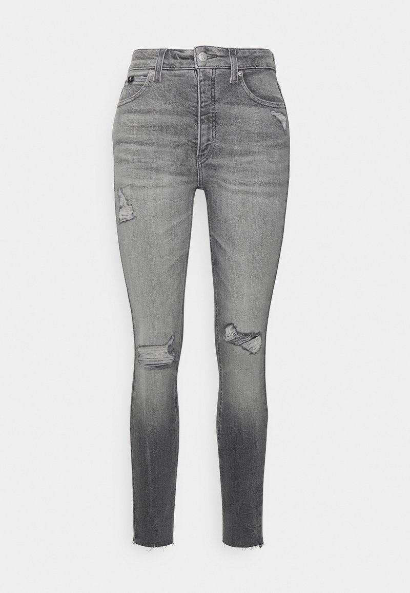 Jeans ajustados en denim gris desgastado, con parches desgastados en los muslos, dobladillo deshilachado y diseño clásico de cinco bolsillos.