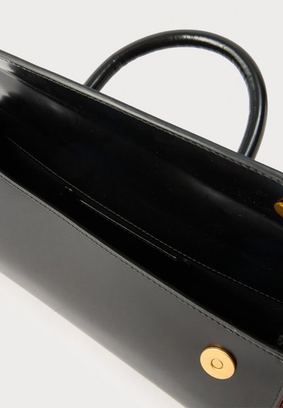 Čierna kožená kabelka s zaobleným uchom a zlatým magnetickým zapínaním, zobrazená mierne otvorená na bielom pozadí.