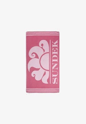 Asciugamano da spiaggia rosa con un grande design floreale bianco e la parola "SUNDEK," accentuato da due strisce bianche lungo i bordi e le estremità frangiate.