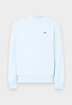 Sweatshirt azul claro feito de um tecido macio. Apresenta decote redondo, punhos canelados e um pequeno logótipo verde da Lacoste no peito.