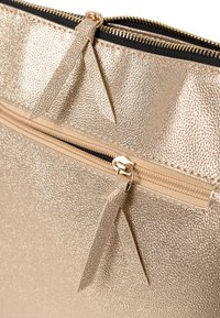 Metalen gouden laptophoezen van textielmateriaal met twee ritsen, voorzien van leren trekbanden en een zwarte binnenvoering.