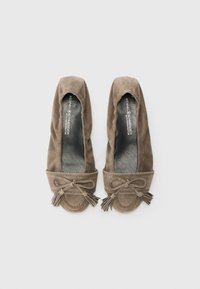 Ballerines en daim marron avec un bout rond et un accent de nœud avec des franges. Empeigne texturée et doublure intérieure douce et lisse.