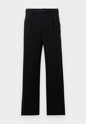 Juodos pritaikytos kelnės, pagamintos iš medvilnės; turi plokščią priekį, matomas siūles ir tiesaus silueto kirpimą. Mygtuko užsegimas juosmens srityje.