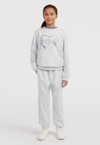 Sudadera gris con el texto 'O'Neill' impreso en un diseño de corazón, combinada con pantalones de chándal grises, ambos de material suave. Zapatillas blancas completan el conjunto.