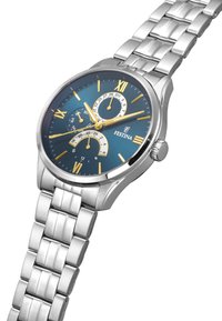 Montre en acier inoxydable argenté avec un cadran bleu, des chiffres romains dorés et des sous-cadrans. Présente une finition polie et un bracelet en métal lié.