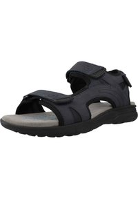 Sandalia negra con correas ajustables, plantilla acolchada y suela de goma. Presenta detalles de malla y un diseño de punta redondeada.