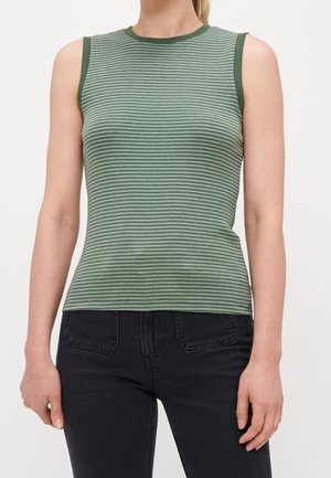 Vrouw draagt een mouwloze groene gestreepte geribde top, gecombineerd met zwarte jeans met hoge taille, kort bij de nek en taille.