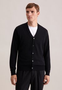 Cardigan noir avec un design en V, des manches longues et des fermetures à boutons. Fabriqué à partir d'un matériau doux avec des cuffs et un ourlet côtelés.