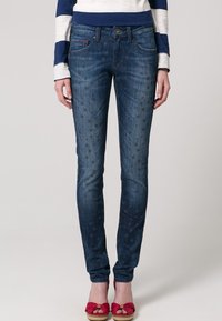 Smaljeans i mörkblått med subtila stjärnmönster, med klassiska fickor, en framknäppning och en midjehöjd på medelhöjd.