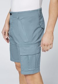 Shorts cargo bleu clair en tissu résistant, dotés de multiples poches, un devant plat et une coupe décontractée.