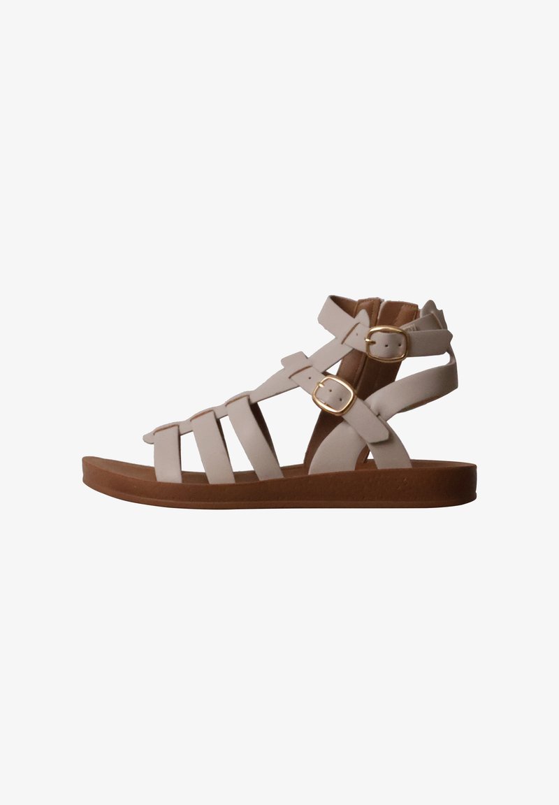 Sandale gladiateur plate beige avec semelle marron, plusieurs brides et deux fermetures à boucles dorées à la cheville et au pied.