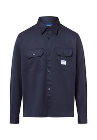 Camisa de botones azul marino de manga larga, con dos bolsillos en el pecho y un pequeño parche de logo. Hecha de tela suave con un cuello clásico.