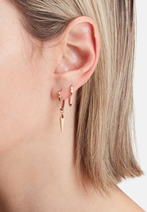 Boucles d'oreilles créoles en or rose avec un charme pointu, présentant une surface polie et un design épuré, suspendues à un fermoir à charnière.