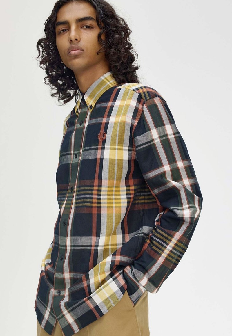 Camicia button-up a quadri con controlli in verde scuro, giallo, arancione e bianco; presenta un orlo curvo, maniche lunghe e un piccolo logo ricamato.