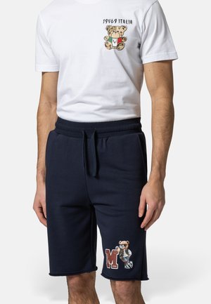 Weißes T-Shirt mit Teddybär und Schriftzug "1969 Italia", kombiniert mit navyblauen Shorts, die einen Teddybär beim Baseballspielen und das Letter-„M“-Design zeigen.