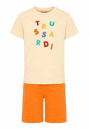 T-shirt cremisi a maniche corte con lettere multicolore sparse e pantaloncini arancioni vivaci fino al ginocchio.