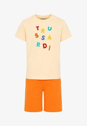 T-shirt cremisi a maniche corte con lettere multicolore sparse e pantaloncini arancioni vivaci fino al ginocchio.