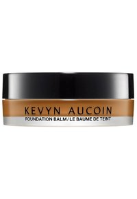 Kevyn Aucoin Foundation Balm in einem runden, schwarzen und klaren Behälter. Das Produkt hat eine warme Tan-Farbe mit glatter Textur.