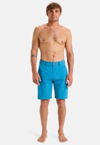 Blue shorts made of lightweight fabric, with a flat front, belt loops, and a single button closure. Hem ends just above the knee.