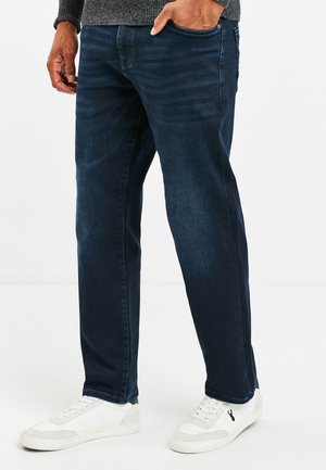Donkerblauwe denim jeans met een rechte pijp, met subtiele textuur en zijzakken. Gecombineerd met witte sneakers.