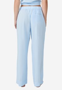Lichtblauwe, wijde broek gemaakt van een zachte stof. Voorzien van een elastische tailleband en een achterzak. Soepele textuur, ontspannen pasvorm.