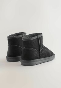Schwarze Wildleder-Stiefeletten mit weicher Innenausstattung, runder Zehenpartie und robuster Gummisohle. Mit gesteppten Details und einem leicht gefalteten Schaft.