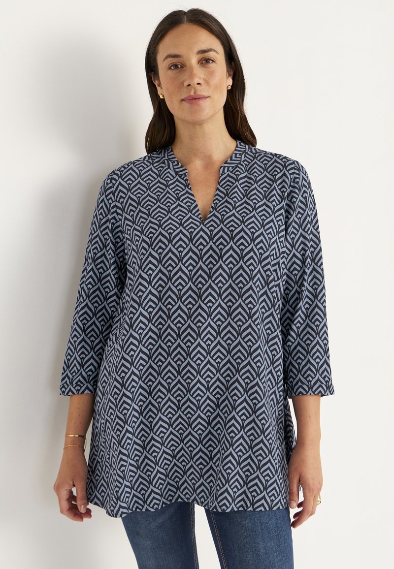 Navy blue tunic with a geometric white pattern, v-neckline, and three-quarter sleeves, made of lightweight fabric.