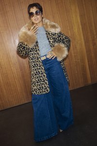 Παλτό με μοτίβο λεοπάρ με συνθετική γούνα στον γιακά και τα μανίκια, γκρι μπλουζάκι, τζιν παντελόνι φαρδιάς γραμμής. Τα αξεσουάρ περιλαμβάνουν μεγάλα γυαλιά ηλίου και δαχτυλίδια.