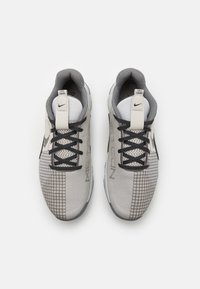 Jasnoszare buty sportowe z teksturowaną siateczkową cholewką, czarnymi akcentami i wzorem w kratkę po bokach. Posiadają czarne sznurowadła i wyściełany kołnierz.