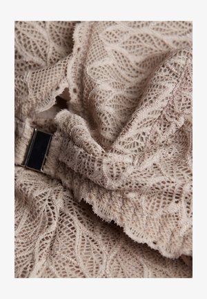 Tissu en dentelle beige présentant des motifs de feuilles complexes et un détail de fermoir en argent, mettant en valeur une apparence douce et texturée.