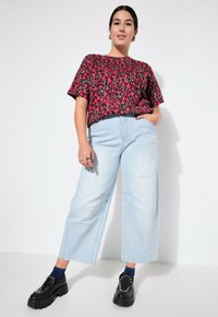 Avskuren svart och röd blommig topp, ljusblå vida jeans och svarta chunky plattformsskor med silverdetaljer och blå strumpor.