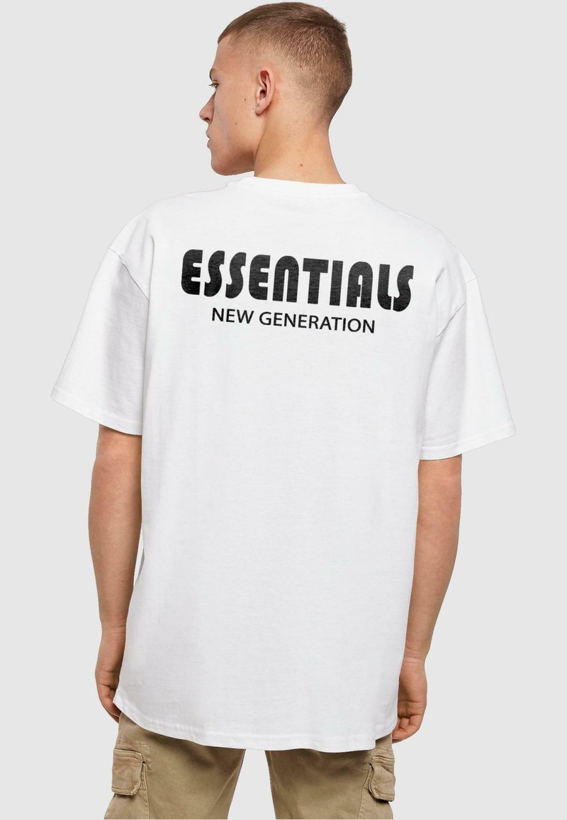 T-shirt en coton blanc avec un texte noir audacieux au dos, indiquant "ESSENTIALS NOUVELLE GÉNÉRATION". Manches courtes et design à coupe décontractée.