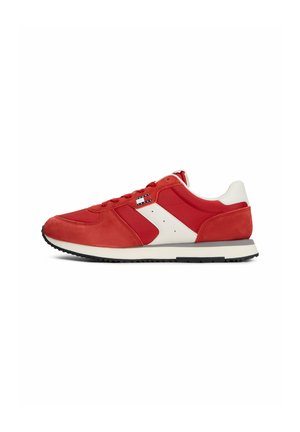 Roter und weißer Sneaker mit niedriger Schaftform, schwarzer Gummisohle, Velours- und Stoffeinsätzen sowie kleinem Flaggenlogo an der Seite.