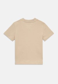 Μπεζ κοντομάνικο μπλουζάκι από βαμβάκι. Διαθέτει στρογγυλή λαιμόκοψη και διπλή ραφή στο στρίφωμα. Η πλάτη έχει μια απλή, χωρίς ραφές σχεδίαση.