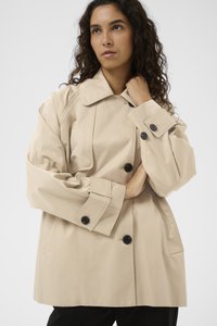 bézs ballonkabát strukturált kivitelben, nagy fekete gombokkal, széles gallérral és oldalzsebekkel. Simább, könnyű anyag.