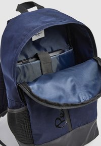 Mochila azul marino con exterior de tela, parte superior redondeada y fondo negro. El interior cuenta con un forro suave y una correa para asegurar los objetos.