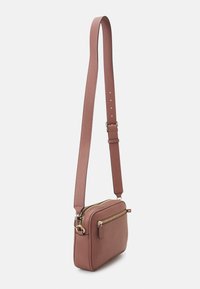 Listonoszka w miękkiej różowej skórze, prostokątny kształt, regulowany pasek, złote akcenty, przednia kieszeń na zamek, teksturowana powierzchnia.