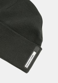 Berretto lavorato a maglia di colore grigio scuro con un motivo testurizzato e un risvolto. Presenta un'etichetta con il marchio cucita sul lato anteriore.