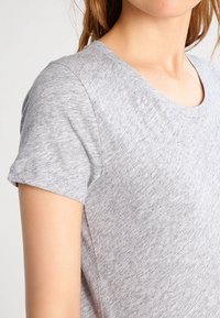 Graues Kurzarm-T-Shirt aus weichem, strukturiertem Stoff. Verfügt über einen runden Halsausschnitt und leicht gerollte Ärmel, mit einer lockeren Passform.