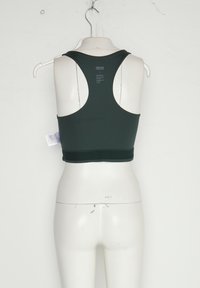 Svart racerback sports-bh hengende på en hvit mannequin mot en ensfarget vegg, som viser bakfra og merkets etikett.