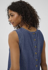 Denimkjole med rund halsudskæring, ærmeløs design og knaplukning bagpå med seks messingknapper. Mørkeblåt stof med en glat tekstur.