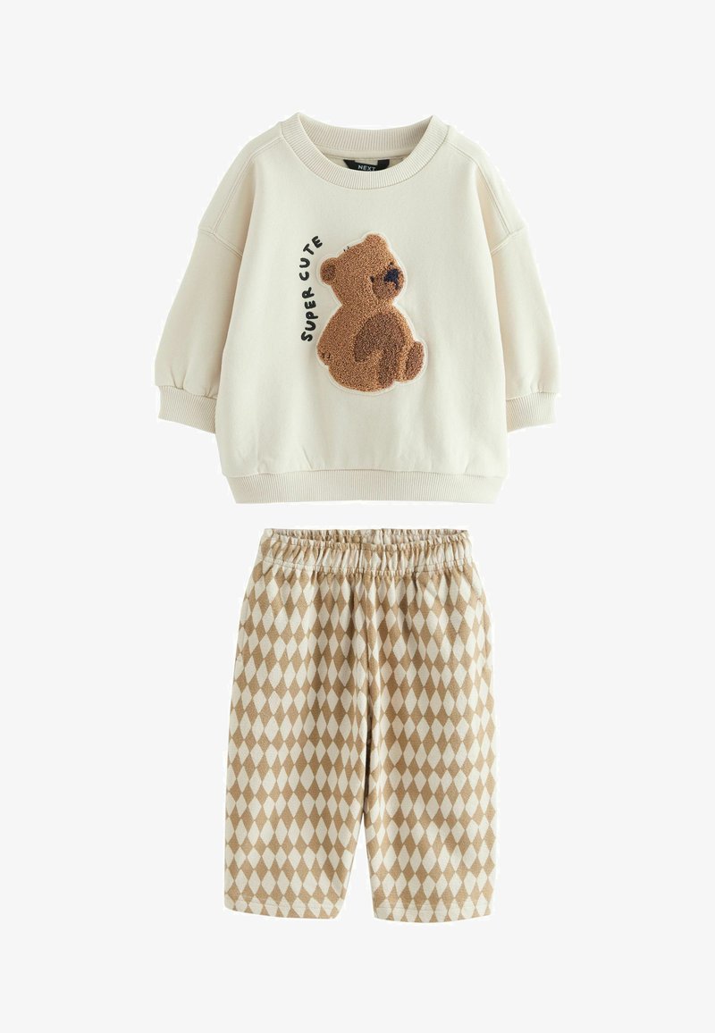 Kremna otroška pulover s dolgimi rokavi z 3D medvedkom in napisom "Super Cute", v kombinaciji s bež in belimi hlačami z elastičnim pasom in diamantnim vzorcem.
