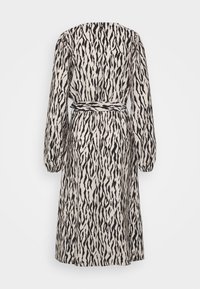 Robe à manches longues en tissu léger, présentant un motif abstrait noir et blanc avec une taille cintrée et une ceinture à nouer.
