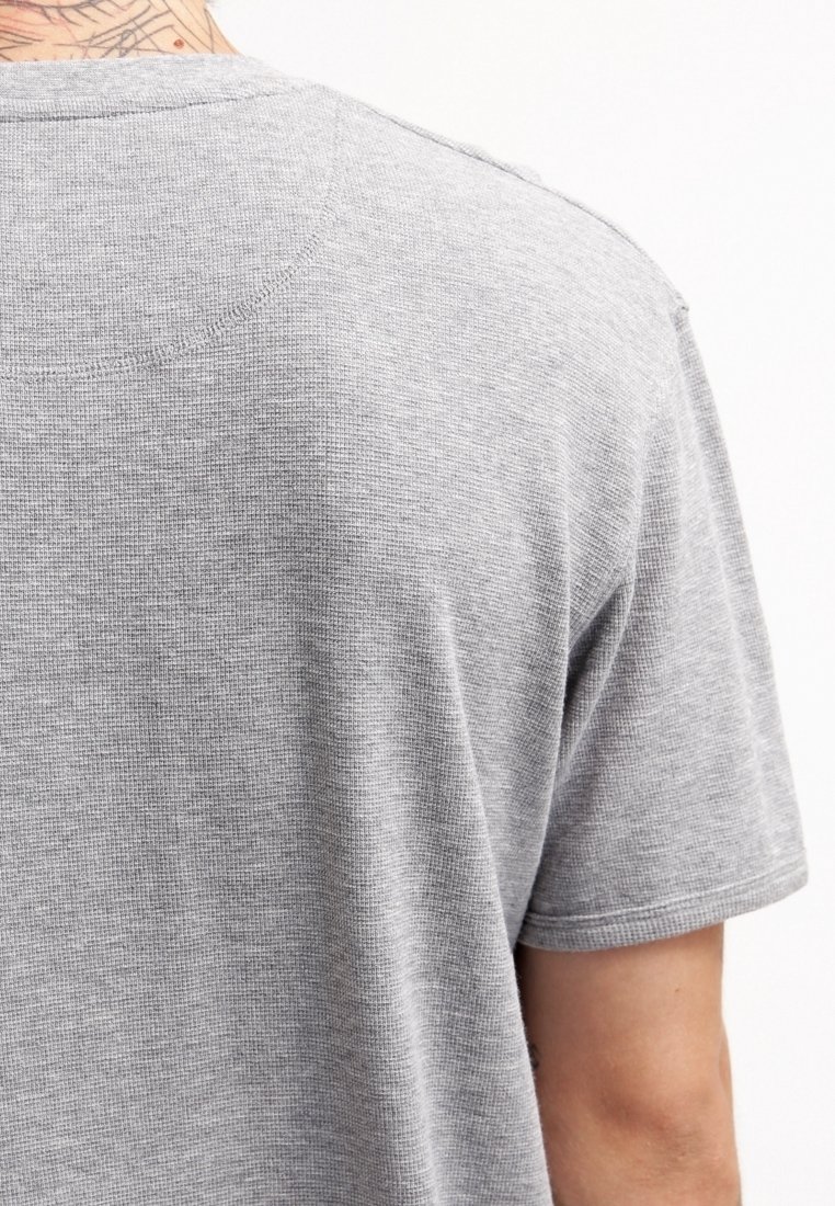 Grå bomullströja med strukturstickning, rund halsringning och korta ärmar, med en avslappnad passform och subtila sömdetaljer.