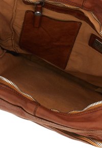 Interno di una borsa in pelle marrone con una texture liscia, caratterizzato da un ampio compartimento principale, una chiusura zip e una tasca piccola.