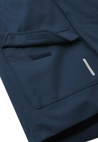 Tessuto impermeabile blu navy con due tasche a chiusura in velcro e un dettaglio a striscia riflettente. Texture liscia, design funzionale.