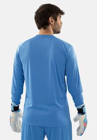 Langarm sportshirt in lichtblauw, gemaakt van gladde, ademende stof. De drager heeft ook keepershandschoenen aan.